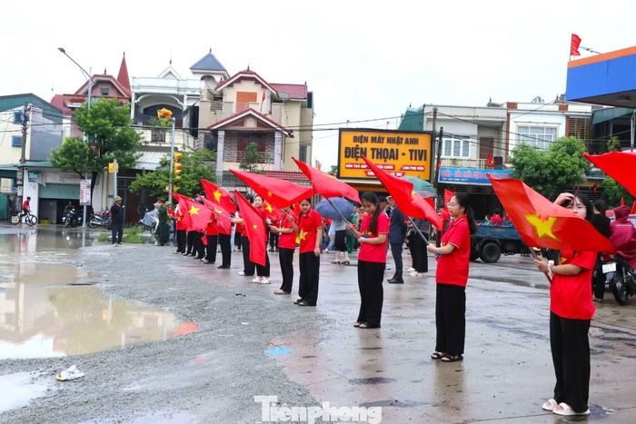 Người dân cầm cờ Tổ quốc đứng hai bên đường, đón liệt sĩ Hoàng Ngọc Thiết trở về.