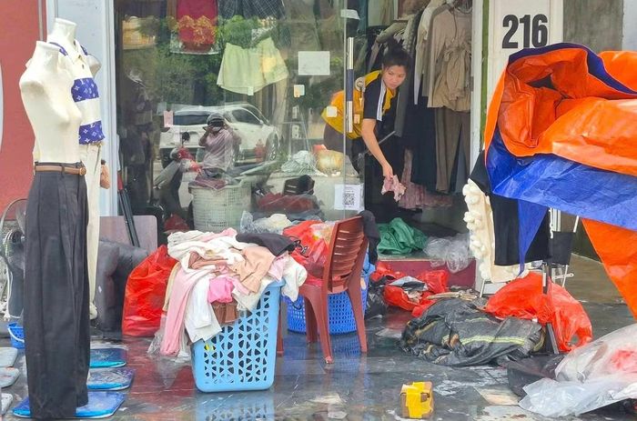 Nhiều shop, cửa hàng bán quần áo ở tuyến đường Nguyễn Văn Cừ bị ngập sâu phải dọn dẹp, phân loại hàng hư hỏng để bỏ đi.