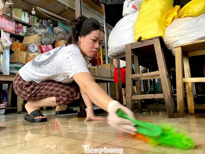 Sau một đêm ngập nước, nền chợ và các khu vực xung quanh phủ đầy bùn đất, rác thải. Những chiếc khăn lau, chổi, xô nước được các tiểu thương tận dụng để làm sạch từng góc cửa hàng.