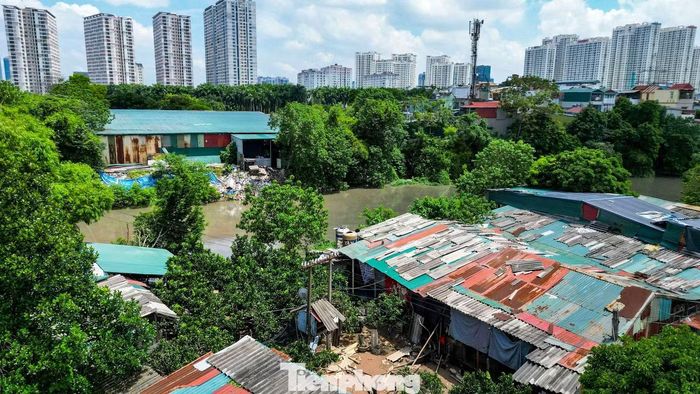Một nhà xưởng có cửa mở thẳng ra phía sông, phía sau chất đống vật liệu bỏ đi và rác thải sinh hoạt.