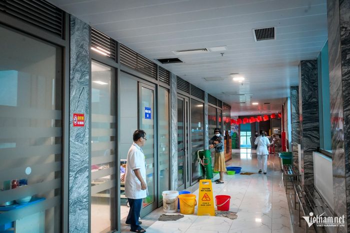 Chị N.T.T.T, nhân viên vệ sinh bệnh viện, cho biết tình trạng nước chảy từ trần nhà xuống sàn tại nhiều vị trí trong bệnh viện đã xuất hiện từ nhiều tháng. Theo chị T., không những trời mưa, trời nắng cũng chảy nước. Tại khu vực buồng bệnh số 1, Khoa Truyền nhiễm, nhiều chiếc xô lớn được đặt trước cửa phòng để hứng nước. Nhân viên vệ sinh phải lau dọn liên tục để hạn chế tình trạng trơn trượt và cách 2-3 giờ phải đổ nước trong xô 1 lần.