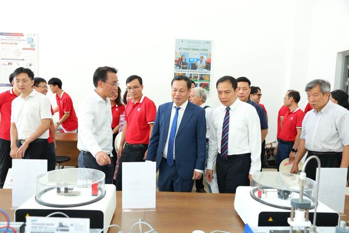 GS.TS Chử Đức Trình (áo trắng, bên trái ảnh), Hiệu trưởng Trường Đại học Công nghệ giới thiệu các phòng thực hành, thí nghiệm. Ảnh: CN