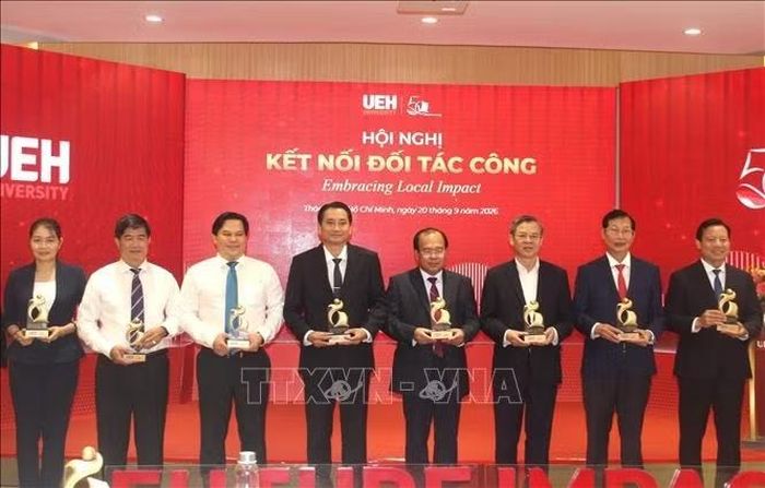 Đại diện các đơn vị đồng hành nhận Biểu trưng UEH hành trình tri thức – con người – tương lai. Ảnh: Mỹ Phương/TTXVN