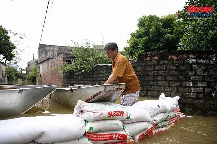 Người dân dùng bao tải tạo lối đi tạm và đưa thuyền qua khu vực ngập sâu.