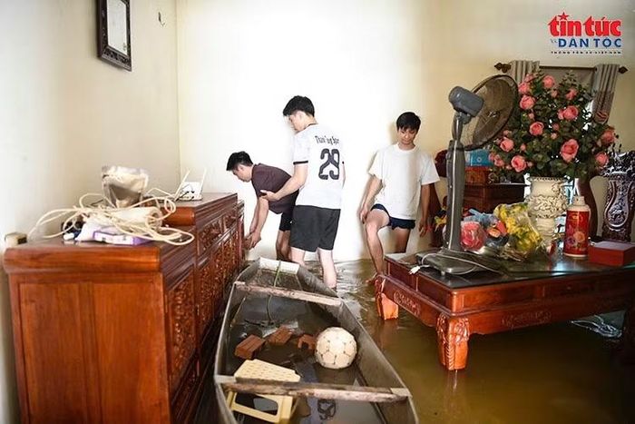Thuyền trở thành phương tiện vận chuyển đồ đạc bên trong căn nhà bị nước lũ bao vây.