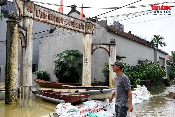 Cổng làng văn hóa Đồng Dâu bị ngập nước. Thuyền và những bao tải được huy động để phục vụ đi lại, gia cố các vị trí xung yếu.