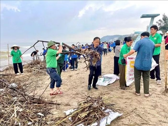 Ước tính có khoảng 6.000m3 rác, củi theo mưa lũ dạt vào bãi biển Sầm Sơn. Ảnh: TTXVN phát