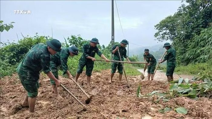 Lực lượng Bộ đội Đồn Biên phòng Ba Nang (Quảng Trị) dọn dẹp đất đá tại vị trí sạt lở, khẩn trương khơi thông tuyến đường phục vụ việc đi lại và hỗ trợ người dân. Ảnh: TTXVN phát