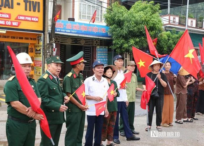Người dân xếp hàng hai bên đường, mang cờ hoa nghẹn ngào đón nhận hài cốt liệt sĩ Hoàng Ngọc Thiết trở về.