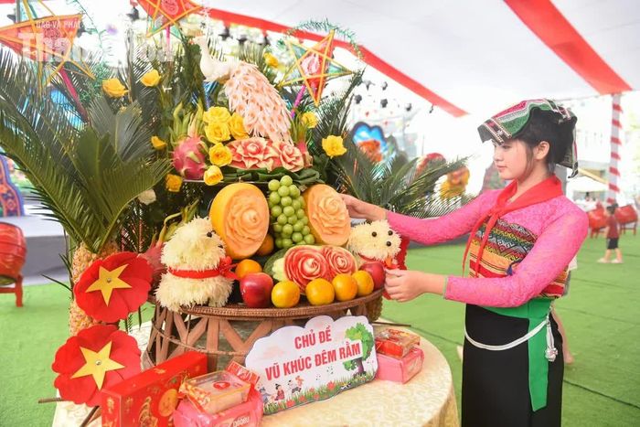 Bàn tay nhỏ nhắn của các em học sinh thoăn thoắt uốn nắn từng múi bưởi thành hình chú cún lông xù ngộ nghĩnh, tỉa vỏ quả đu đủ thành đóa hoa rực rỡ, mang sắc màu mùa thu về bên mâm cỗ.