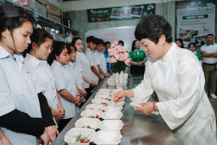Cô Thanh Châu (áo dài trắng) hướng dẫn các học viên Điếc trang trí bánh kem