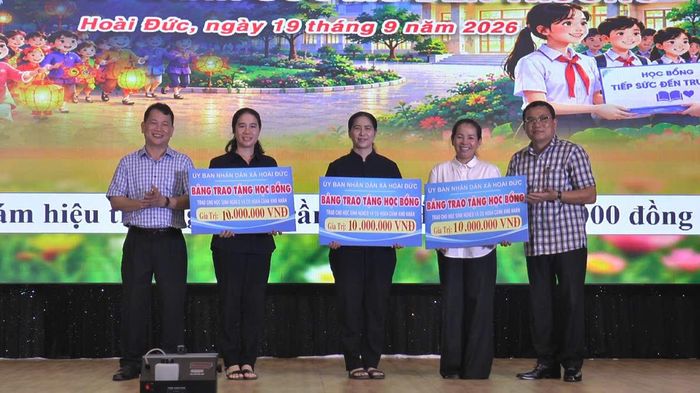 Chủ tịch UBND xã Hoài Đức Trần Đình Trang (ngoài cùng bên phải) trao học bổng cho đại diện các trường học có học sinh khó khăn