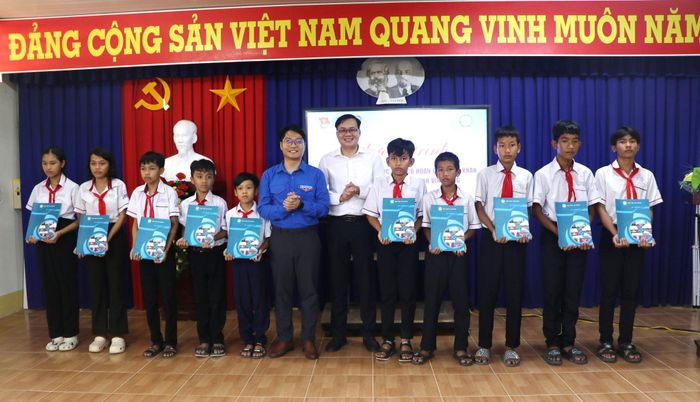 TS Tạ Đình Hòa, Bí thư Đoàn Thanh niên Học viện Tài chính, Phó Trưởng Khoa Ngoại ngữ và Ủy viên Ban Chấp hành Trung ương Đoàn, Phó Bí thư Thường trực Tỉnh đoàn, Chủ tịch Hội Liên hiệp Thanh niên Việt Nam tỉnh Vĩnh Long Nguyễn Thanh Nhã trao học bổng cho các em học sinh có hoàn cảnh khó khăn tại xã Vĩnh Xuân. Ảnh: Ngọc Bích
