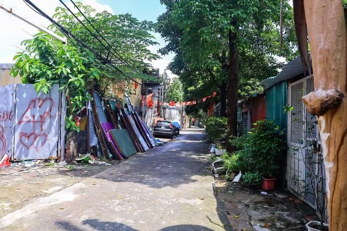Lối đi hẹp dẫn vào khu dân cư ven sông cũng biến thành bãi tập kết vật liệu xây dựng. Tôn vách, khung nhôm kính xếp tràn ra mép đường.