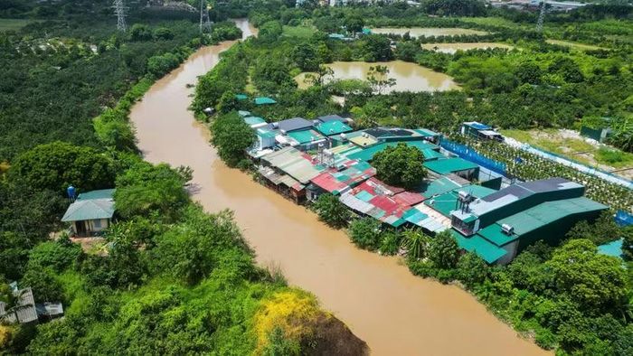 Không gian thoát lũ bị xâm thực nghiêm trọng. Lều lán, xưởng tạm quây tôn kín mít đua nhau vươn ra sát dòng nước đục ngầu, tạo thành một vách ngăn chắn ngang bờ bãi.