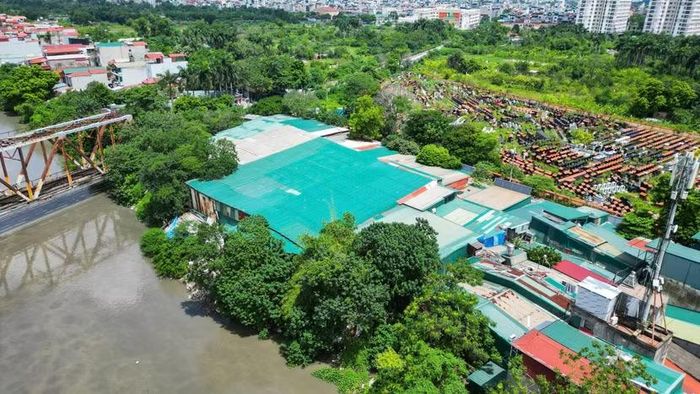 Khối nhà xưởng khổng lồ nằm kề một bãi tập kết vật liệu công nghiệp rộng hàng nghìn mét vuông. Toàn bộ áp lực từ các cọc thép, phế liệu nặng nề đang đè trực tiếp lên hành lang bảo vệ luồng lạch.