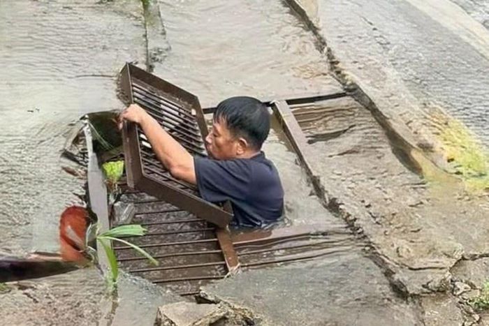 Ông Long ngụp xuống dòng nước đục kéo rác mắc tại miệng cống trên quốc lộ 27 chiều 19/9.