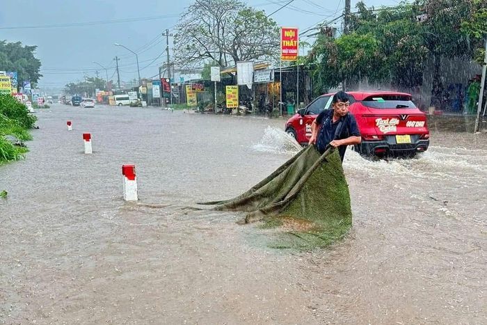 Rác thải và cành cây mắc kín miệng cống khiến nước thoát chậm trên quốc lộ 27 chiều 19/9. Ông Long cùng người dân dọn rác, khơi thông dòng chảy.