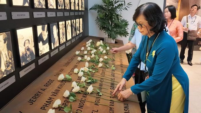 Khách tham quan đặt cành hoa trắng tưởng nhớ các phóng viên chiến trường đã hy sinh trong chiến tranh Việt Nam. Ảnh: Hữu Duyên - TTXVN