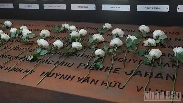 Khách tham quan đặt hoa hồng trắng tại khu vực tưởng niệm các phóng viên chiến trường đã tử nạn trong chiến tranh Đông Dương. (Ảnh: LINH BẢO)