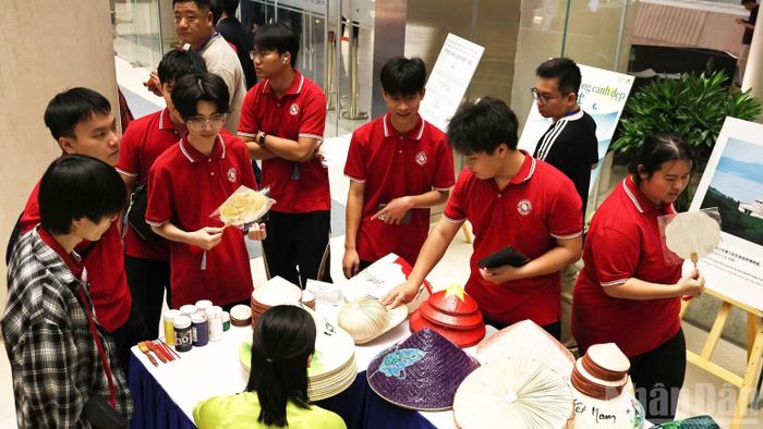 Các bạn sinh viên tìm hiểu nghệ thuật vẽ nón lá của Việt Nam. (Ảnh: DIỆU NGỌC)