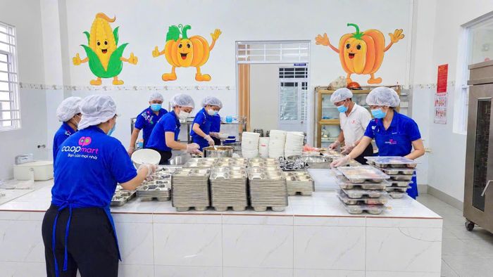 Nhân viên Co.opmart Long Xuyên chuẩn bị suất ăn trước khi vận chuyển đến trường. Ảnh MINH XUÂN