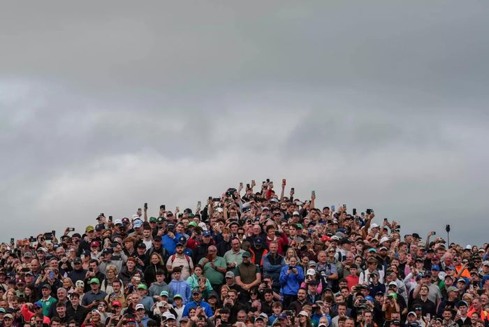  Khán giả theo dõi golfer Ireland Shane Lowry thực hiện cú putt tại hố 18 trong khuôn khổ Irish Open trên sân Trump International Golf Links ở Doonbeg, Ireland. Sau chiến thắng tại Irish Open hồi tuần trước, tay golf Shane Lowry tiếp tục thi đấu tại giải BMW PGA Championship ở Wentworth, London. Vận động viên golf người Ireland duy trì phong độ ổn định với ba vòng đấu đạt điểm số dưới 70 gậy, qua đó tạm đứng thứ 21 với thành tích 11 gậy dưới par. Kết quả này giúp vận động viên Shane Lowry nhiều khả năng nhận khoản tiền thưởng hơn 100.000 USD tại BMW PGA Championship. Trước đó, chiến thắng tại Irish Open ở Doonbeg đã đánh dấu màn trở lại đáng chú ý của tay golf Ireland sau một thời gian tìm lại phong độ tốt nhất. (Nguồn: Springfield News-Sun) 