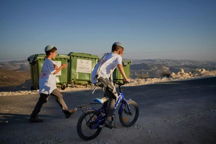  Một em nhỏ Israel mang theo khẩu súng đồ chơi trong lễ khánh thành giáo đường Do Thái tại khu định cư Homesh ở Bờ Tây. Hàng trăm người định cư Israel tập trung tại Homesh, miền Bắc Bờ Tây, để tham dự lễ khánh thành một giáo đường Do Thái tại khu định cư được khôi phục. Những người tham dự hát, nhảy múa và mang theo các cuốn kinh Torah trong buổi lễ. Một số người định cư mang theo súng trường. Israel đã giải thể khu định cư Homesh vào năm 2005, trước khi chính thức phê duyệt việc tái lập khu định cư này vào năm 2025. Người Palestine tại làng Burqa gần đó cho rằng, sự hiện diện của khu định cư làm hạn chế quyền tiếp cận đất nông nghiệp thuộc sở hữu tư nhân. Trong khi đó, Israel viện dẫn các vấn đề an ninh cũng như mối liên hệ lịch sử và tôn giáo với khu vực này để bảo vệ chính sách định cư. (Nguồn: Southeast Missourian) 