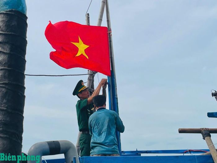 Cán bộ Đồn Biên phòng Tuy Hòa, Bộ đội Biên phòng tỉnh Đắk Lắk hỗ trợ ngư dân treo cờ Tổ quốc trước khi ra khơi. Ảnh: Ngọc Lân