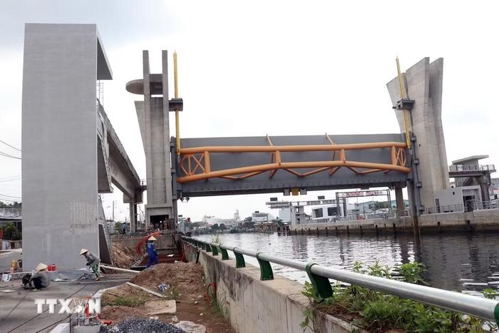 Cống kiểm soát triều Phú Định cơ bản hoàn thành phần xây dựng, hiện đang hoàn thiện các hạng mục đường, vỉa hè, thảm nhựa cho tuyến đường ven kênh. (Ảnh: Tiến Lực/TTXVN)
