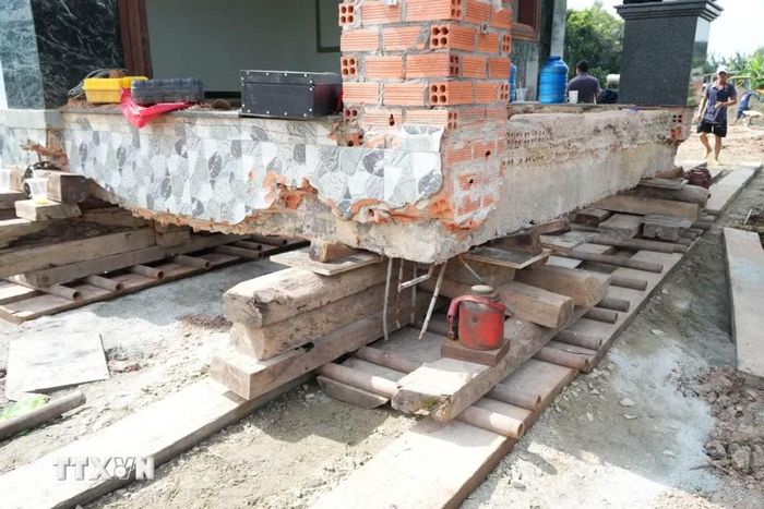 Căn nhà nguyên trạng được nâng lên hệ thống con lăn, ván gỗ, kích thủy lực và các thiết bị chuyên dụng để di chuyển đến vị trí mới. (Ảnh: Sỹ Tuyên/TTXVN)