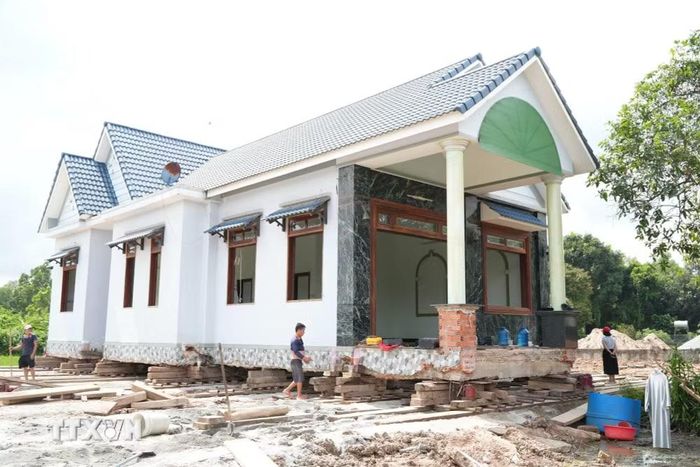 Căn nhà nguyên trạng được nâng lên hệ thống con lăn, ván gỗ, kích thủy lực và các thiết bị chuyên dụng để di chuyển đến vị trí mới. (Ảnh: Sỹ Tuyên/TTXVN)