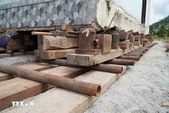 Căn nhà nguyên trạng được nâng lên hệ thống con lăn, ván gỗ, kích thủy lực và các thiết bị chuyên dụng để di chuyển đến vị trí mới. (Ảnh: Sỹ Tuyên/TTXVN)