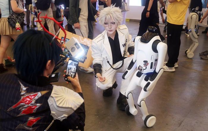 Một cosplayer chụp ảnh cùng robot biến hình T1 của Qiyuan Robotics tại triển lãm ChinaJoy 2026 ở Thượng Hải. Ảnh: chinadailyhk.com/
