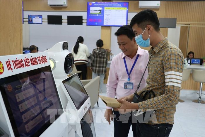 Cán bộ Trung tâm Phục vụ hành chính công hướng dẫn người dân thao tác tìm kiếm thông tin về thủ tục hành chính qua hệ thống AI. Ảnh: K GỬIH - TTXVN