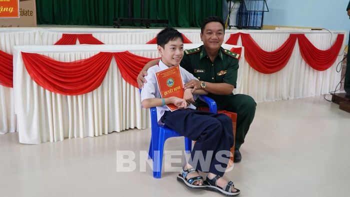 Trung tá Nguyễn Minh Vương, Chính trị viên Đồn Biên phòng Tam Thanh (bên phải) trao Quyết định hỗ trợ theo chương trình "Nâng bước em tới trường" cho em Võ Xuân Trãi. Ảnh: Quốc Dũng - TTXVN