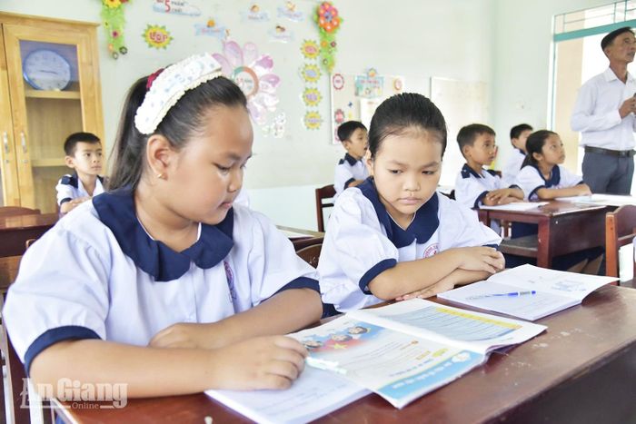 Học sinh Trường Tiểu học và Trung học cơ sở Hòa Thuận dùng chung sách giáo khoa trong giờ học.