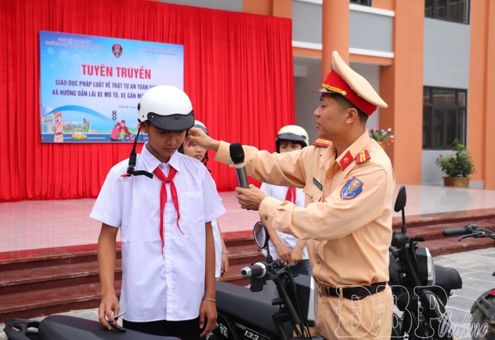 Cán bộ Phòng Cảnh sát giao thông hướng dẫn học sinh đội mũ bảo hiểm đạt chuẩn.