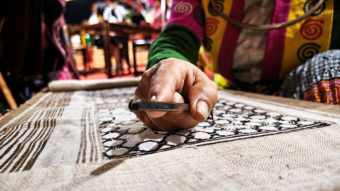 Đôi bàn tay khéo léo của người phụ nữ Mông tỉ mỉ vẽ sáp ong, tạo nên những đường hoa văn truyền thống trên nền vải lanh.