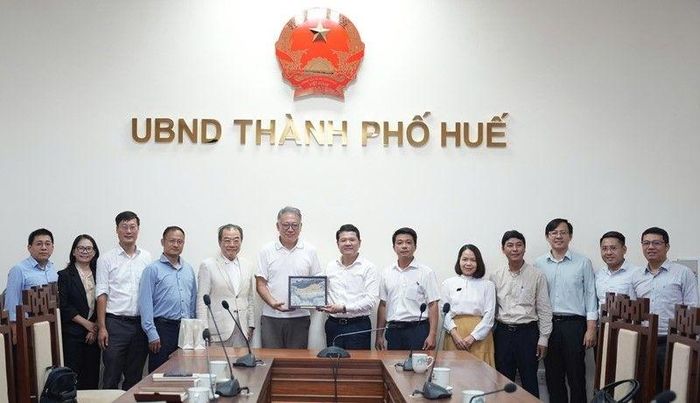 Lãnh đạo thành phố tặng quà và chụp hình lưu niệm.