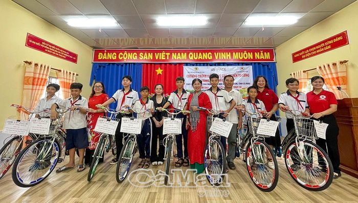 Học sinh vùng ven biển Cà Mau vui mừng bên chiếc xe đạp mới được Hội Chữ thập đỏ vận động trao tặng. (Ảnh chụp tại xã Cái Ðôi Vàm).
