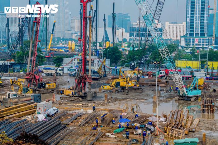 Cần cẩu, máy đào, máy khoan cọc nhồi và xe tải chở vật liệu được huy động phục vụ các hạng mục đang triển khai. Nhiều mũi thi công hoạt động cùng lúc trên diện tích rộng.