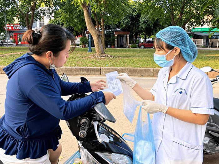 Cán bộ Trạm Y tế xã Ô Diên phát Cloramin B và hướng dẫn người dân vệ sinh, khử khuẩn tại hộ gia đình. Ảnh: PV