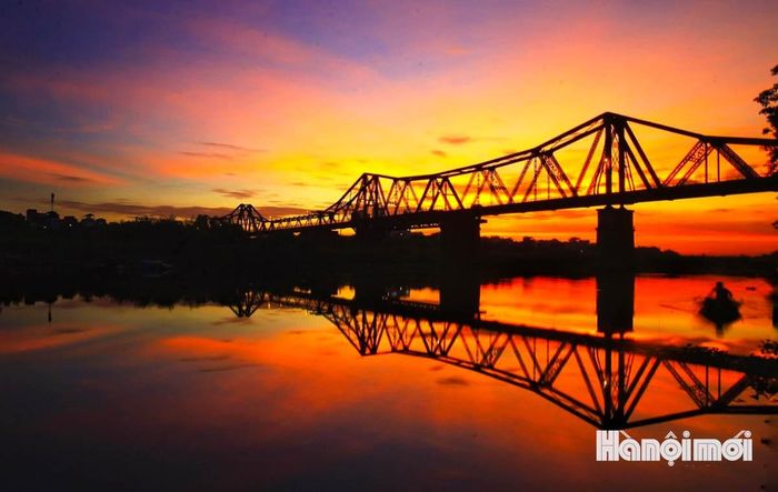 Cầu Long Biên soi bóng xuống dòng sông Hồng, tạo nên một bức tranh bình minh vừa khoáng đạt vừa nên thơ. Ảnh: NAG Nguyễn Quốc Vượng