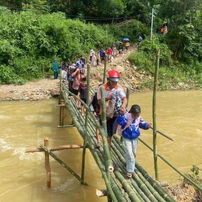 Người dân và học sinh qua cầu tạm sau khi tuyến đường bị chia cắt do sạt lở. Ảnh: Y.N.