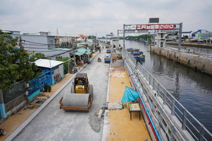 Trên hai đoạn đường Phú Định và Đình An Tài ven kênh Đôi (khu vực qua cống Phú Định), nhà thầu đang lu nền, thảm bê tông nhựa và lát gạch vỉa hè. 