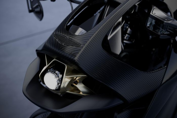 Cụm đèn trước được bao quanh bởi thanh trang trí bên hông đặc trưng của Aston Martin, kết hợp các đường nét thân xe carbon và khe gió hình lưỡi liềm nhằm tối ưu luồng khí, đồng thời nhấn mạnh thiết kế khí động học hướng về phía trước.