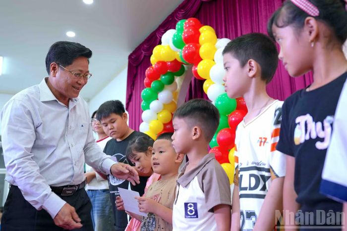Phó Chủ tịch Hội đồng nhân dân tỉnh Bùi Tấn Bảy (bìa trái) trao tặng học bổng cho các cháu thiếu nhi nhân buổi họp mặt. (Ảnh: HỮU TÙNG)