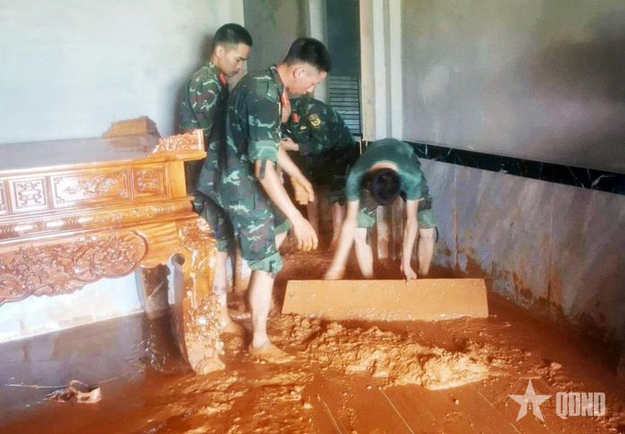 Bùn đất ngập sâu trong nhà dân được bộ đội khẩn trương thu dọn, vệ sinh sau khi lũ rút.