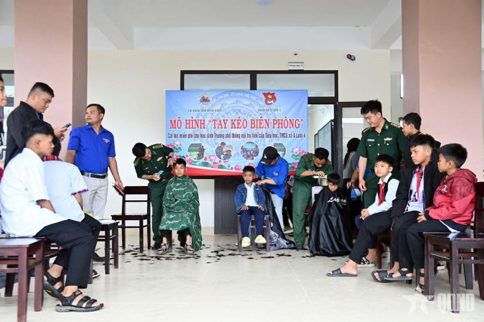 Cắt tóc cho các em học sinh trong mô hình “Tay kéo Biên phòng”. 